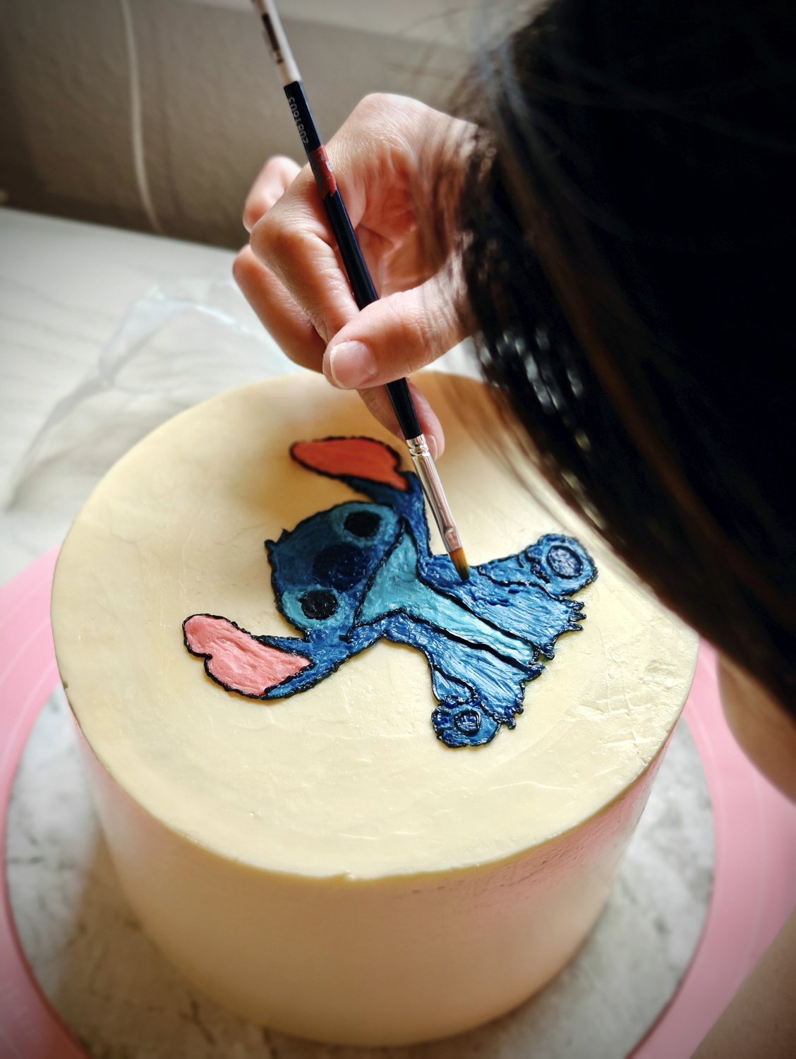 Grace hand-painting a cake with delicate detail